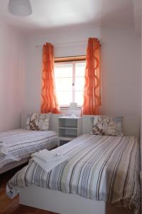 1 dormitorio con 2 camas y una ventana con cortinas de color naranja en Baleal Holiday House en Baleal