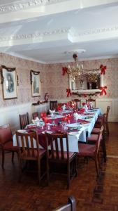 uma grande sala de jantar com uma longa mesa com decorações vermelhas em Neuadd Arms Hotel em Llanwrtyd Wells