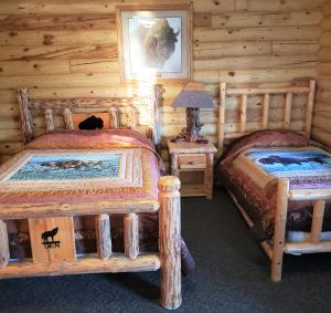 a bedroom with two beds in a log cabin at Wolf Den Log Cabin Motel and RV Park in Thayne