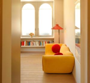 einen gelben Stuhl im Wohnzimmer mit zwei Fenstern in der Unterkunft Sopra Il Posta in SantʼOmobono Imagna