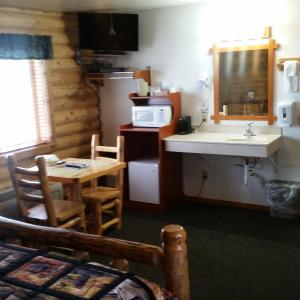 Wolf Den Log Cabin Motel and RV Park في Thayne: مطبخ مع حوض وطاولة مع ميكروويف