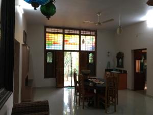 ein Esszimmer mit einem Tisch, Stühlen und Buntglasfenstern in der Unterkunft CoconutCrazy! Homestay in Ottappālam