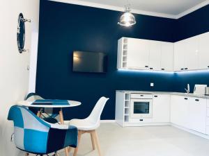 a kitchen with blue walls and a table and chairs at Apartament Pod Żaglami in Gdynia