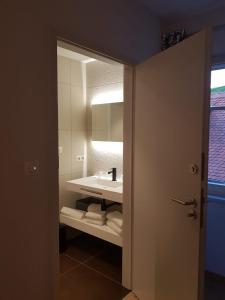 ein Badezimmer mit einem weißen Waschbecken und einem Spiegel in der Unterkunft Caveau de l'ami Fritz in Ribeauvillé