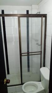 a bathroom with a toilet and a glass shower at Hotel Santafe Suite in Bogotá