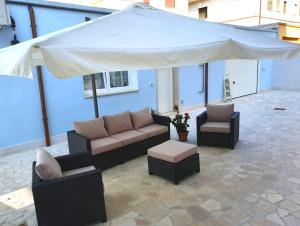 patio z kanapami i dużym białym parasolem w obiekcie B&B Locanda Criloro w mieście Pescara