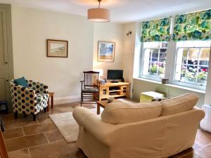 uma sala de estar com um sofá e duas janelas em Lauras Townhouse Apartments Garrard's Retreat em Bath