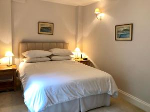 um quarto com uma grande cama branca e 2 candeeiros em Lauras Townhouse Apartments Garrard's Retreat em Bath