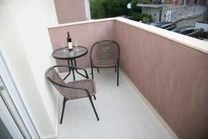 a balcony with two chairs and a table with a bottle of wine at Apartments Mira in Tivat