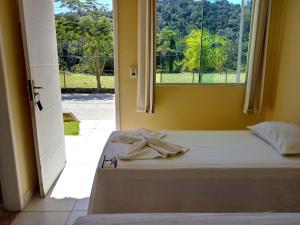 a bedroom with a bed and a window with a view at Pousada Santo Antônio in Piraí