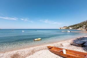 a wooden boat sitting on a beach next to the water at Apartments Ljujić in Kruče