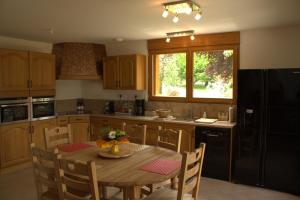 a kitchen with a wooden table and a black refrigerator at Heavens Gate in Saint-Pierre-de-Soucy