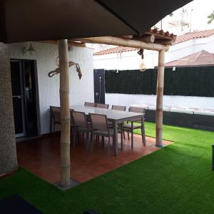 een patio met een tafel en stoelen onder een parasol bij Ca Martina Sonora Golf in Maspalomas