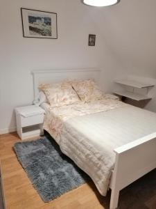 a bedroom with a white bed and a rug at Chambres d'Hôtes Chez Marilou in Aulnay-sous-Bois