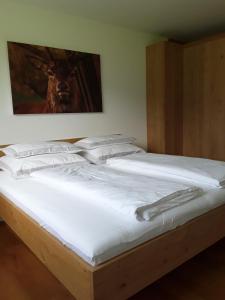 a large bed with white sheets and pillows on it at Appartment Hirschberg in Bizau