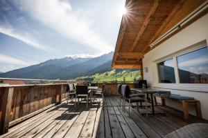 a deck with chairs and tables and a view of mountains at no.dreizehn in Neustift im Stubaital