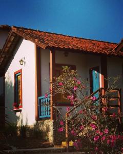 una casa con flores rosas delante de ella en Vila das Artes Chales en Lavras Novas