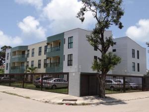 an apartment building with a tree in front of it at Porto Dreams Flat in Porto De Galinhas