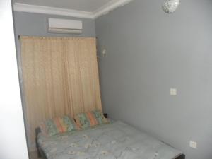 Un dormitorio pequeño con una cama y una ventana. en Biso Inn, en Alimosho