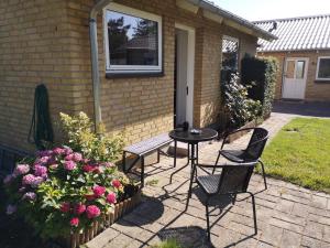 een patio met een tafel, stoelen en bloemen bij Commuter room for one or two people in Munkebo