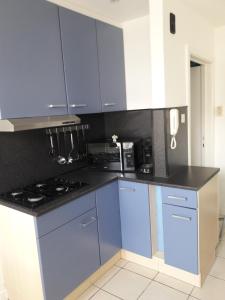 eine Küche mit blauen Schränken und schwarzen Arbeitsplatten in der Unterkunft 2 slaapkamer appartement op de zeedijk van Oostende. in Ostende