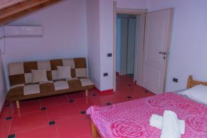 a bedroom with a bed and a couch and a pink floor at Leonida Resort in Donji Štoj