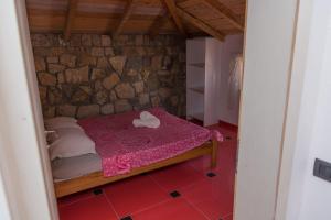 a small bed in a room with a stone wall at Leonida Resort in Donji Štoj