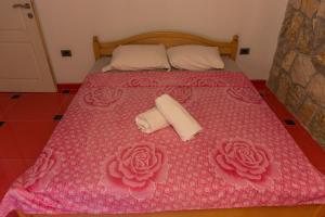 a pink bed with two towels and roses on it at Leonida Resort in Donji Štoj