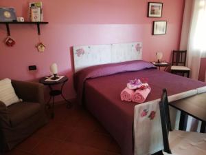 アドリアにあるB&B LA Garzettaのピンクの壁のベッド1台、椅子が備わるベッドルーム1室が備わります。