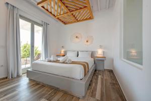 a white bedroom with a bed and a large window at Osom Resort in Ornos