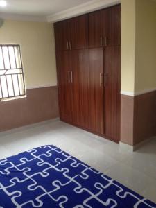 a room with a bed and a wooden cabinet at TJ Cottage in Ilorin