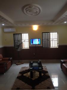 a living room with a table and a tv on the wall at TJ Cottage in Ilorin