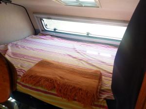 un piccolo letto in una camera con finestra di INTO THE WILD - CAMPER a Montargano