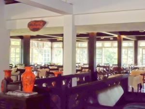 un comedor con mesas, sillas y ventanas en Kithulgala Rest House, en Kitulgala
