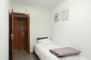 1 dormitorio con cama blanca y puerta de madera en Cosy Apartment Fira Barcelona en Barcelona