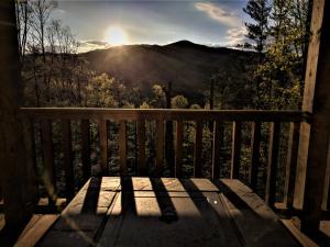 un banc en bois installé sur une terrasse couverte offrant une vue sur les montagnes. dans l'établissement Smokies Overlook Lodge, à Waynesville