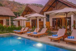 a resort pool with lounge chairs and umbrellas at Cozy Cottages Lombok in Senggigi
