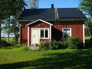 a red house with a white door in a field at Levomäki Farm Cottages in Ypäjä