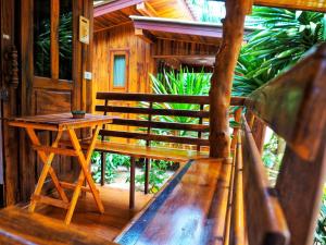 a wooden bench and a table on a porch at Baansuan Resort in Don Sak