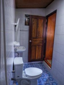 a bathroom with a toilet and a sink and a door at Baansuan Resort in Don Sak