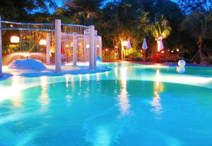 a large swimming pool at night with lights at Birds and Bees Resort in Pattaya South