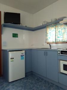 a kitchen with white cabinets and a white refrigerator at Beach Haven Caravan Park in San Remo