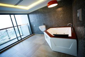 a bathroom with a bath tub and a large window at Coventina Lake Suites in Dhaka