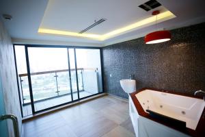 a bathroom with a tub and a large window at Coventina Lake Suites in Dhaka