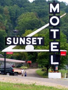 a sign for a sunset gas station with people standing outside at Sunset Motel in Athens