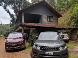 two cars parked in front of a house at Kwality Estate in Madikeri