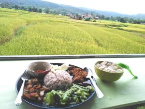 a plate of food on a table next to a field at ชมนาโฮมสเตย์บ้านนาคำ in Ban Bun Yun