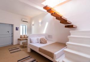 a white room with a bed and a staircase at Sunset Nest in Plaka Milou