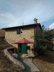 a stone house with a table and a red umbrella at Casetta in Sassi in Varzi