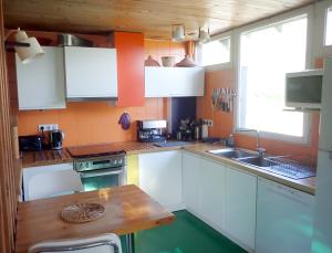 a kitchen with white cabinets and a wooden table at Maison CAILLE in Embrun